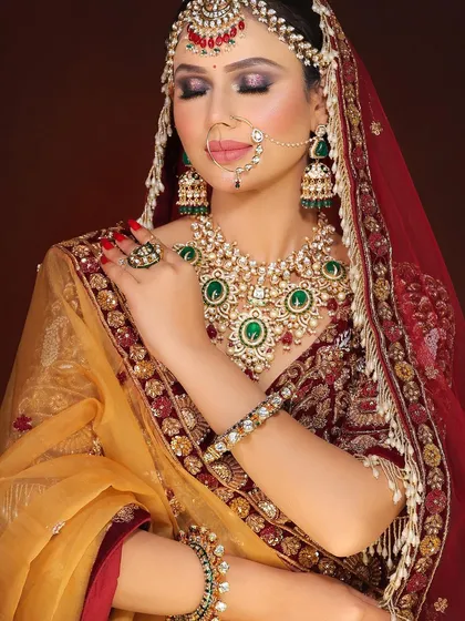 This bride's look is a masterclass in traditional elegance. The makeup enhances her features while complementing the magnificent emerald and polki jewelry set.