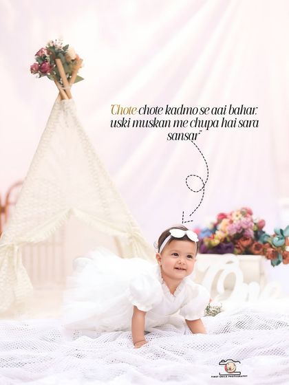 A baby girl crawls across a soft white blanket during her first birthday shoot. The airy teepee and floral details create a whimsical and pure atmosphere for this adorable action shot.