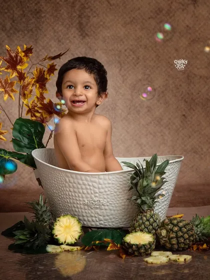 A fun and fruity bubble bath! This little boy is surrounded by pineapples, adding a tropical twist to his splash time.