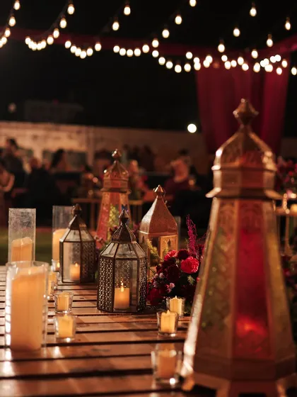 For the picnic-style seating at the Sufi sangeet, the tables were low wooden pallets adorned with Moroccan lanterns, glowing candles, and deep burgundy florals. The look was rustic, moody, and incredibly romantic.