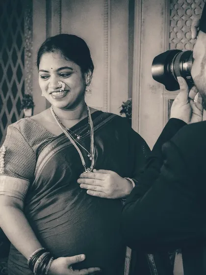 A detailed shot focusing on the mother-to-be's radiant smile and traditional jewelry. The composition draws attention to her happiness and the beautiful details of her attire, including her nose ring and necklace.