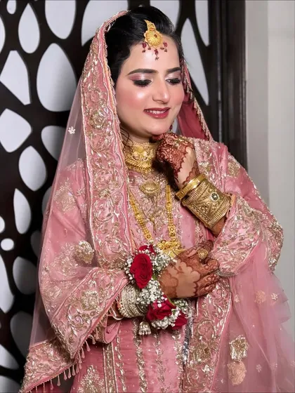 A smiling shot of the client, her happiness radiating. The soft pink makeup and gold jewelry create a look of timeless elegance.