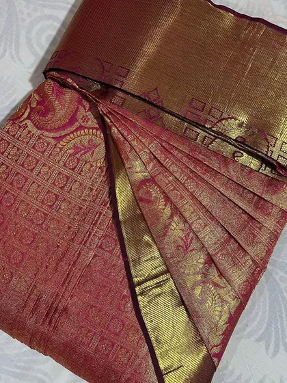 A pink and gold brocade saree, folded to protect its intricate details.