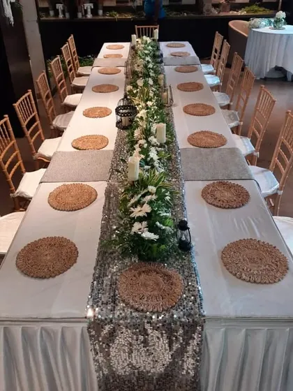 A closer look at the sophisticated table setting, featuring woven placemats and a centerpiece of white flowers and candles.
