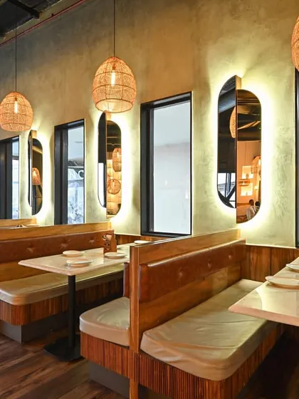 We designed intimate booth seating areas using a combination of wood paneling and upholstered benches. The backlit, pill shaped mirrors add depth and a touch of modern elegance, providing a sense of privacy while reflecting the restaurant's ambient light.