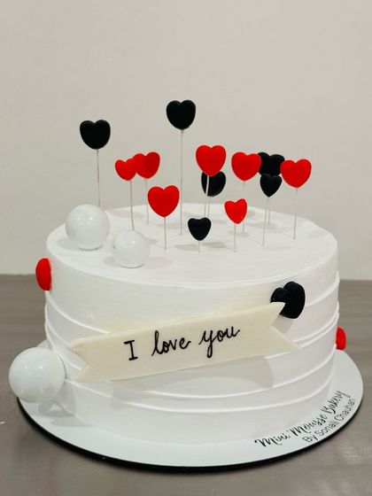 Expressing love with this elegant black and red heart cake. The floating heart toppers and 'I love you' banner make it a perfect choice for an anniversary or romantic gesture.