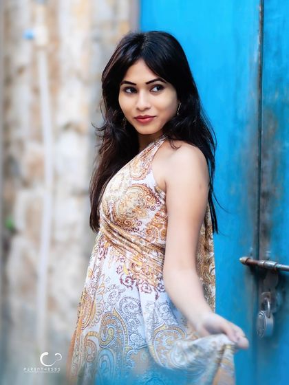 A playful and charming portrait against a bright blue door. The composition is fun and full of character.