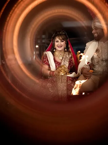 A creative and joyful shot of the couple during a wedding ritual, captured through a ring of fire or light painting for an artistic effect.
