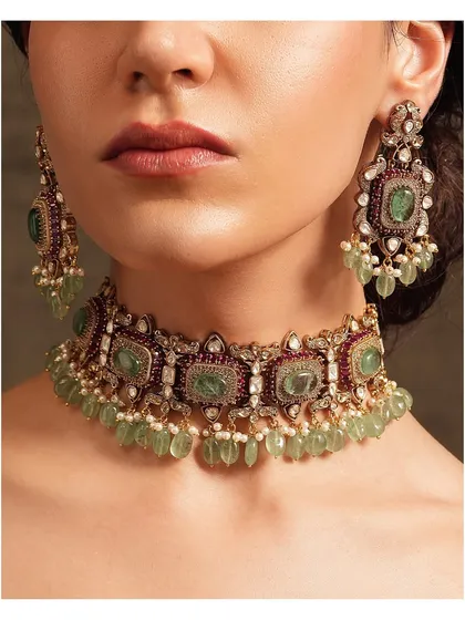 This regal choker combines deep green emeralds with rubies and polki, finished with delicate light green bead drops for a touch of elegance.
