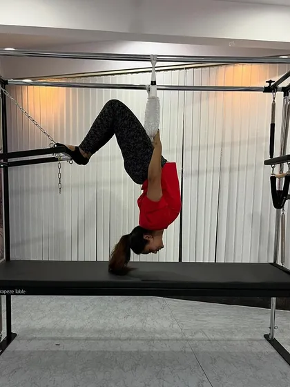 An inverted hanging exercise using the fuzzy straps on the Cadillac, which is excellent for spinal decompression and strengthening the entire posterior chain.