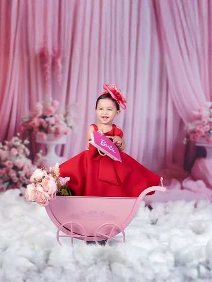 A big smile from our little Barbie. Her joy is contagious as she sits in her pink pram, surrounded by flowers and fluffy clouds.