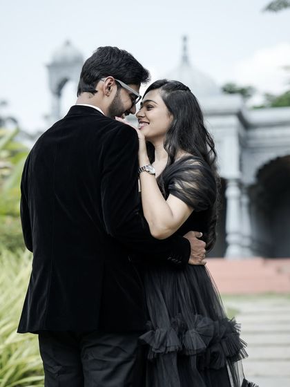 A sweet, over-the-shoulder shot of a couple sharing an intimate moment, dressed in elegant black formal wear.