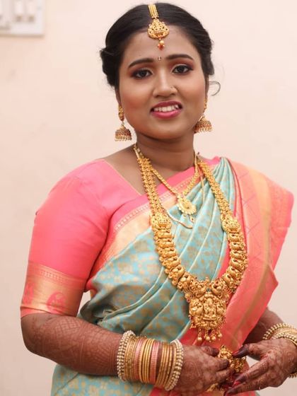 A classic South Indian bridal portrait. This look features traditional temple jewelry, a neat updo, and makeup that highlights her features with a soft glow, perfect for her Muhurtham.