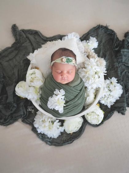 This top-down view shows the full composition, with the dark green fabric creating a beautiful frame around the baby.