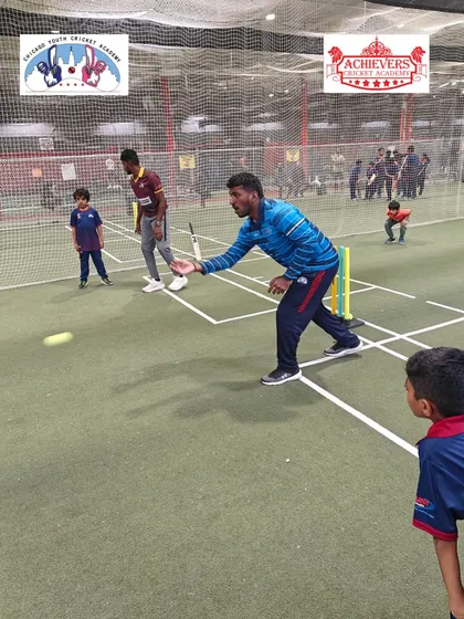 Coach Prashant demonstrating a bowling technique during an indoor session at the CYCA facility in Chicago.