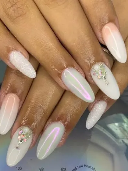 A beautiful and elegant bridal look. This set features a soft white ombre base with pearlescent chrome, sugar glitter accent nails, and delicate crystal placements.