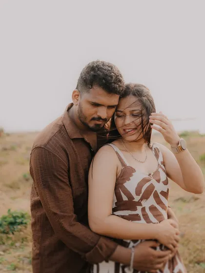 An intimate embrace in a field of tall grass. The wind blowing through the bride's hair adds a touch of wild, natural beauty to this romantic shot.