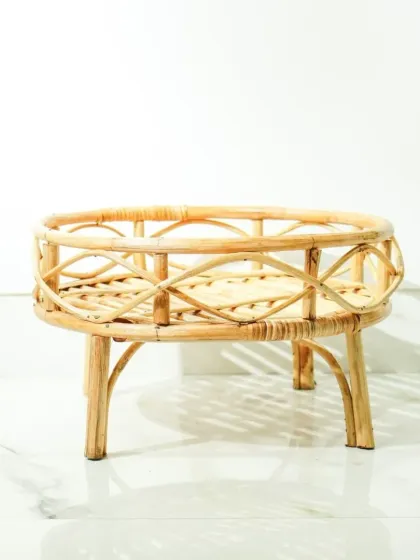This low rattan plant stand or tray table features an elegant, curved leg design and a decorative woven railing. It's a beautiful way to elevate a potted plant or serve as a small, occasional table.