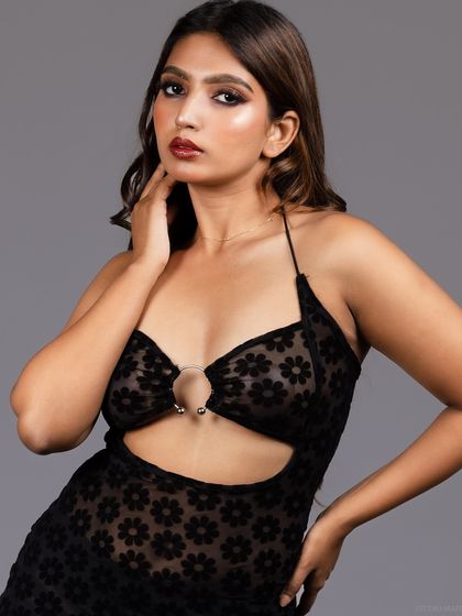 A three-quarter shot of the model in the sheer black dress, showing her pose and the dress's design.