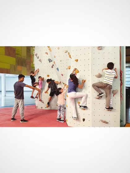 Our kids bouldering sessions are all about fun, safe exploration. A coach guides a group of young climbers on a beginner friendly wall, helping them learn basic climbing techniques, build confidence, and work together in a playful environment.