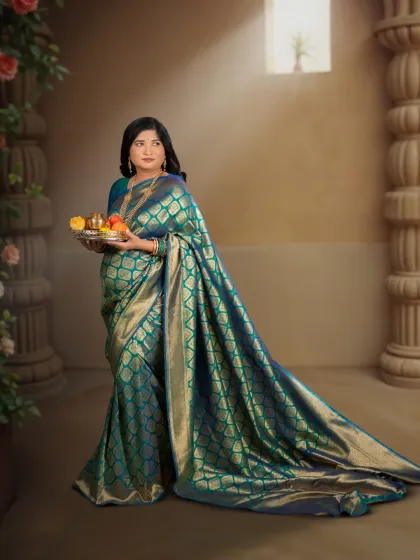 A timeless maternity portrait celebrating the grace of motherhood. This mother-to-be is captured in a classic studio setting, draped in an elegant teal and gold silk saree, creating a regal and artistic memory of her pregnancy.