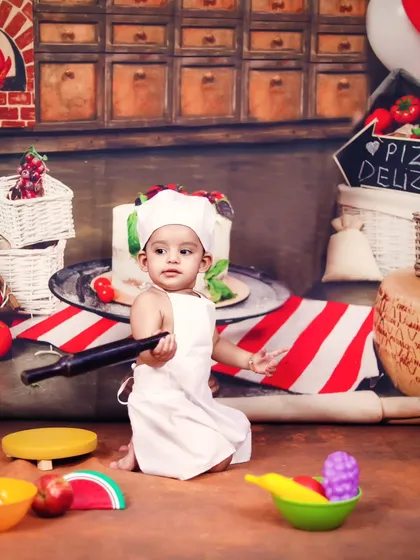 This baby chef means business, holding a rolling pin and ready to make some pizza.