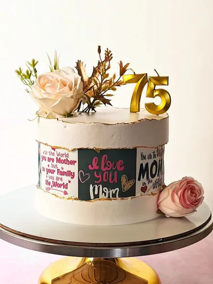 A heartfelt cake for a 75th birthday, featuring a fault line design that reveals loving messages for Mom. The cake is topped with fresh roses and gold number candles.