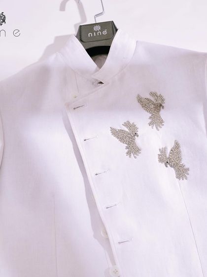 A clean, minimalist shot of our white angrakha-style jacket. The three silver-colored birds are the centerpiece, a statement of quiet confidence and exquisite taste.