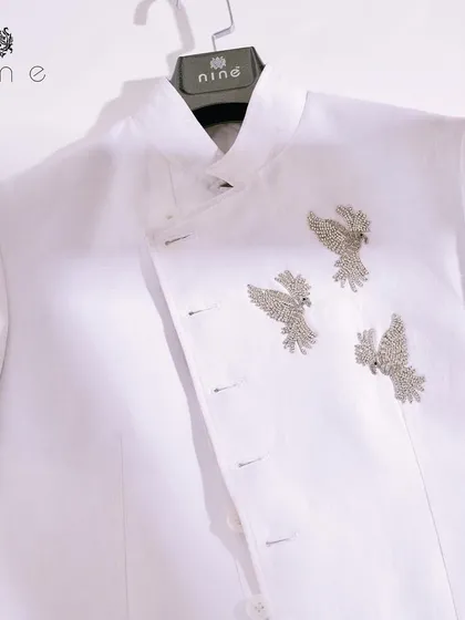 A clean, minimalist shot of our white angrakha-style jacket. The three silver-colored birds are the centerpiece, a statement of quiet confidence and exquisite taste.