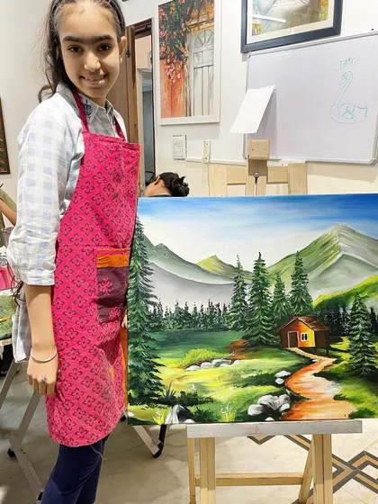This student proudly displays her finished landscape painting. In my classes, we learn how to create depth, mix natural colors, and paint elements like mountains, trees, and water to bring scenic views to life on canvas.