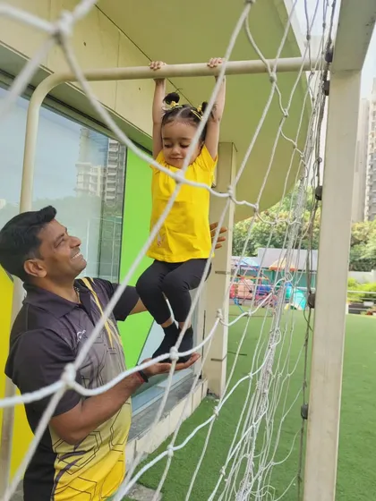 A coach assists a young girl on the climbing net, highlighting our commitment to personalized attention and safety during all physical activities at our Summer Fungama.