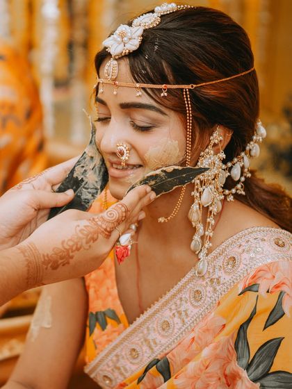 A close-up of the Haldi ritual, where leaves are used to apply the turmeric paste, highlighting the traditional and serene aspects of the ceremony.