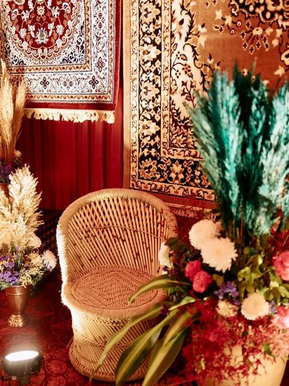 A simple wicker chair becomes a beautiful decor element when placed amidst vibrant floral arrangements and against a backdrop of rich Persian rugs.