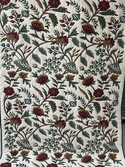 An elegant quilt with a large-scale floral embroidery pattern.
