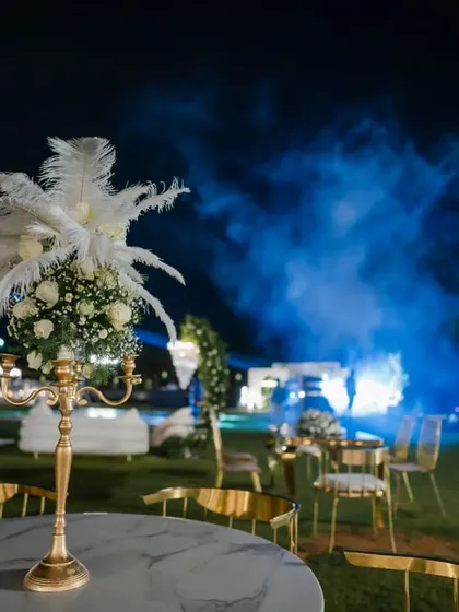 A close-up of a table centerpiece from an elegant 40th birthday party. I used a classic gold candelabra base and topped it with a delicate arrangement of white roses, baby's breath, and soft white feathers to add a touch of timeless charm and sophistication.