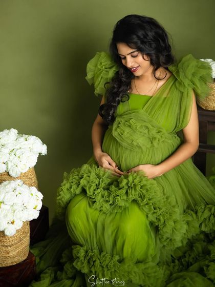 A tender moment captured as the mom-to-be looks down at her bump, surrounded by a beautiful green and white color palette.