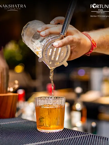 A close-up of a cocktail being poured, capturing the rich amber color and the skill of our bartender.