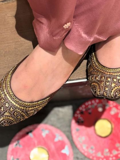 A top-down view of the classic brown and gold woven juttis, showcasing their beautiful pattern and expert craftsmanship.