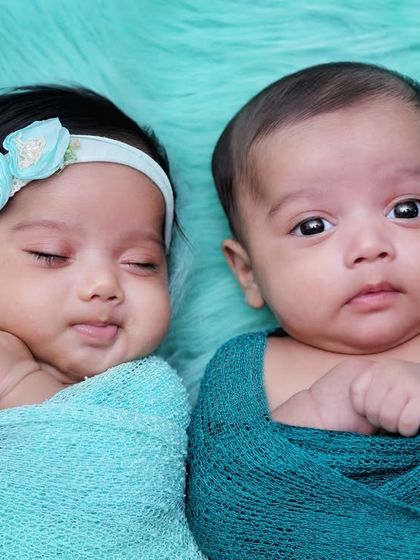 A beautiful portrait of newborn twins, one sleeping and one awake. This shot perfectly captures a real, unscripted moment between them.