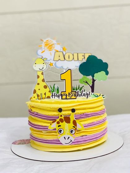 A sweet giraffe-themed cake for a first birthday, with yellow and purple stripes.