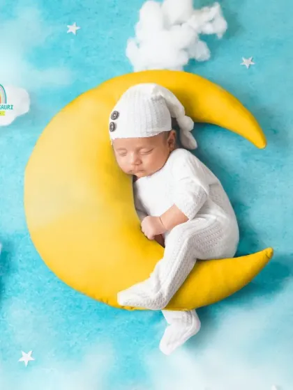 A sweet newborn dressed in white, sleeping soundly on a crescent moon prop. This classic "Twinkle Twinkle Little Star" theme is a favorite among parents.
