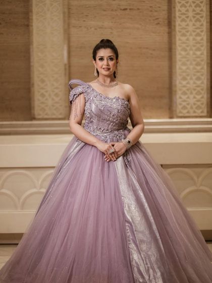 A full-length view of the lavender ball gown, showing its voluminous skirt and the elegant drape of the one-shoulder design.