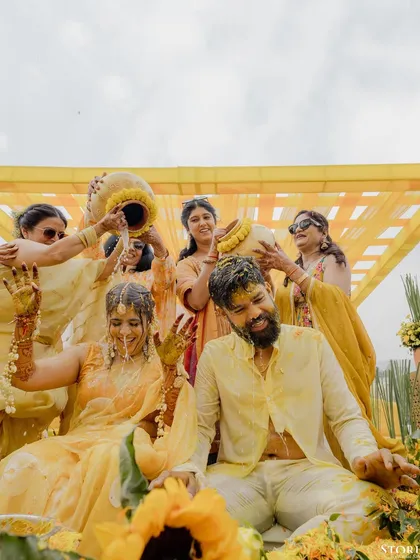 A fun-filled shot of the couple being doused with water from traditional pots by their family and friends.
