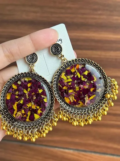 These stunning handmade earrings are made with real dried flower petals preserved in resin, set in a traditional jhumka-style frame.