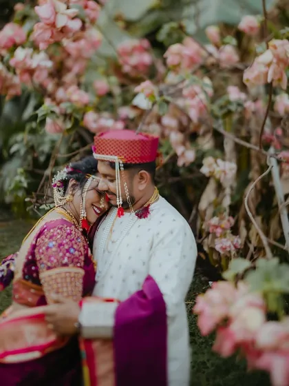 A tender moment between a Maharashtrian couple in their wedding attire, surrounded by blooming flowers. This portrait showcases their connection and the beauty of their traditional outfits.