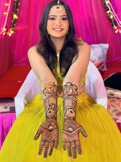 A smiling bride proudly displaying her intricate bridal henna.