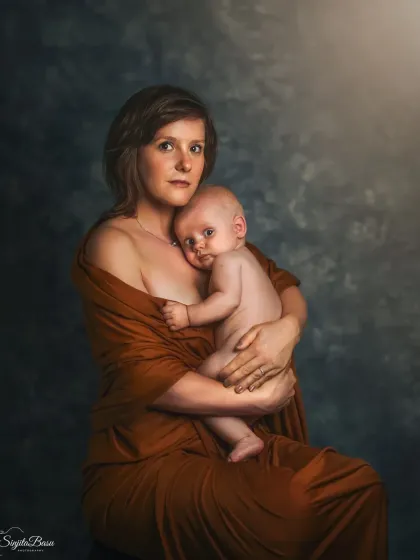 This portrait captures the classic "Madonna and Child" essence, a mother holding her infant in a timeless embrace. The painterly light and moody background focus all attention on the intimate bond and the baby's curious gaze, creating a true family heirloom.