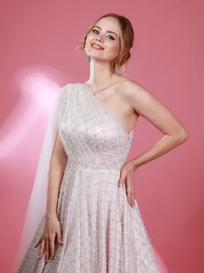 A confident pose from Irina Rudakova in her white gown, with a soft light flare adding a touch of magic to the shot.
