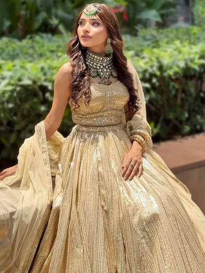 A full-length shot of the golden lehenga look. This is a great example of a modern, elegant bridal style.