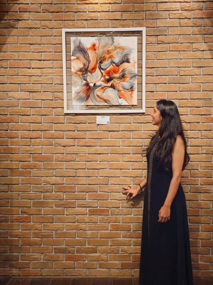 The artist posing with her work against a rustic brick wall at our Sublime Galleria Hyderabad location.